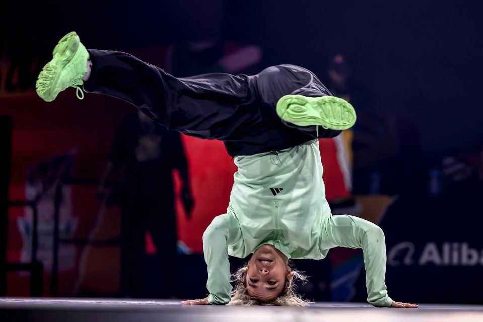 a person doing a handstand in front of a sign that says omega