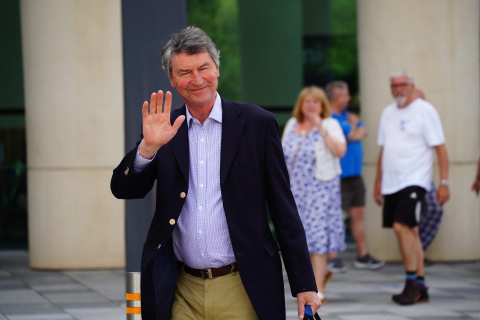 a man in a suit waving his hand in front of a group of people