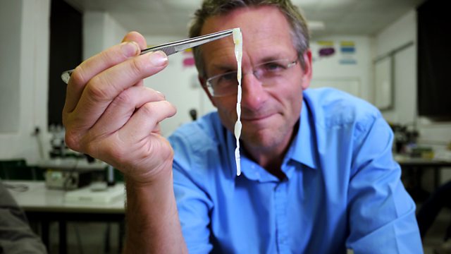 a man in a blue shirt is holding a piece of paper with tweezers