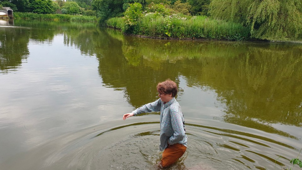 a person standing in a body of water with trees in the background