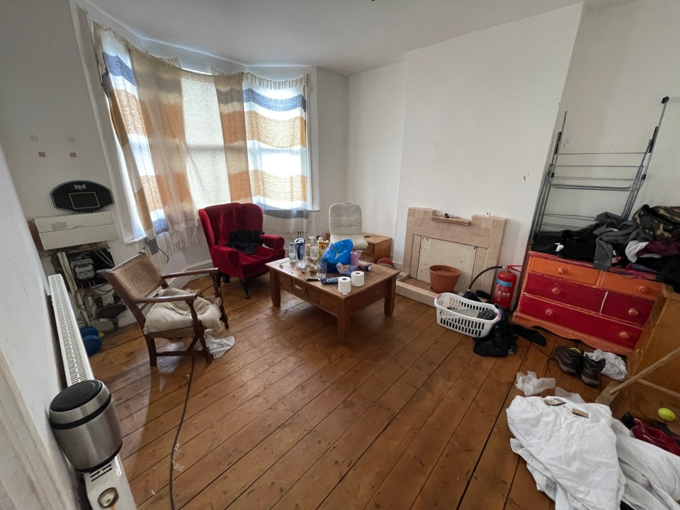 a messy living room with a coffee table and chairs