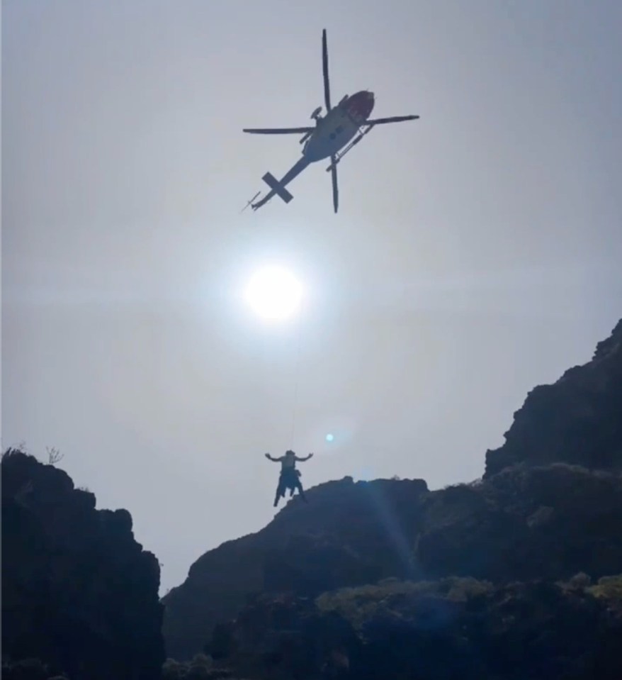 a helicopter is flying over a person on a mountain