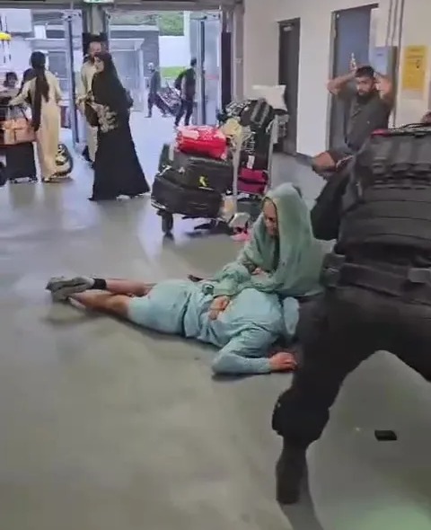 Fahir appeared to be comforted by an older woman as he lied on the floor at Manchester Airport