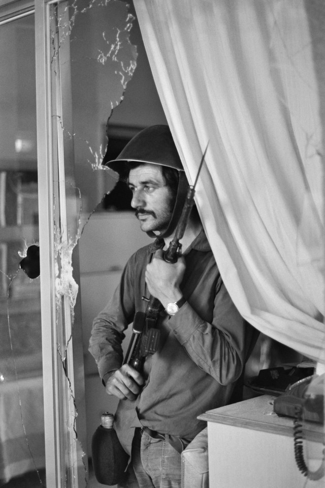 A volunteer stands behind a broken window in 1974 at the Ledra Palace Hotel