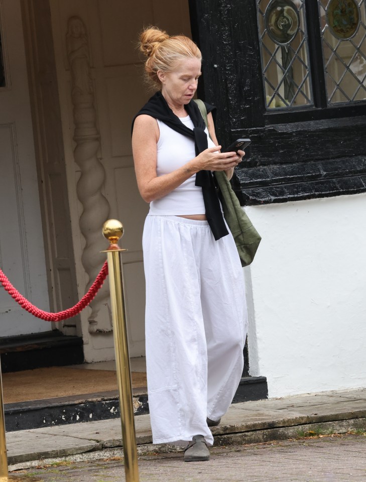 a woman in white pants is looking at her phone