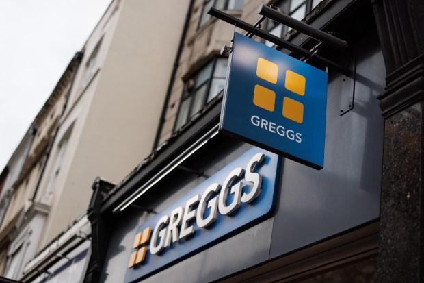 a sign that says greggs hangs from the side of a building