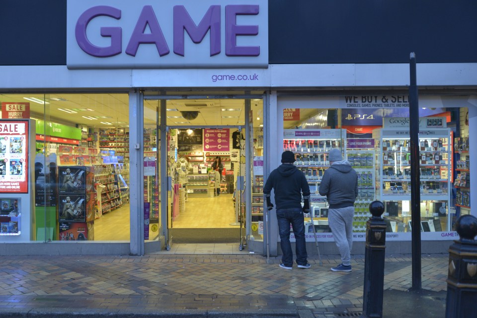 Two people looking at a Game store window.