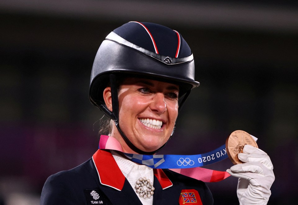 a woman wearing a helmet and holding a medal that says tokyo 2020