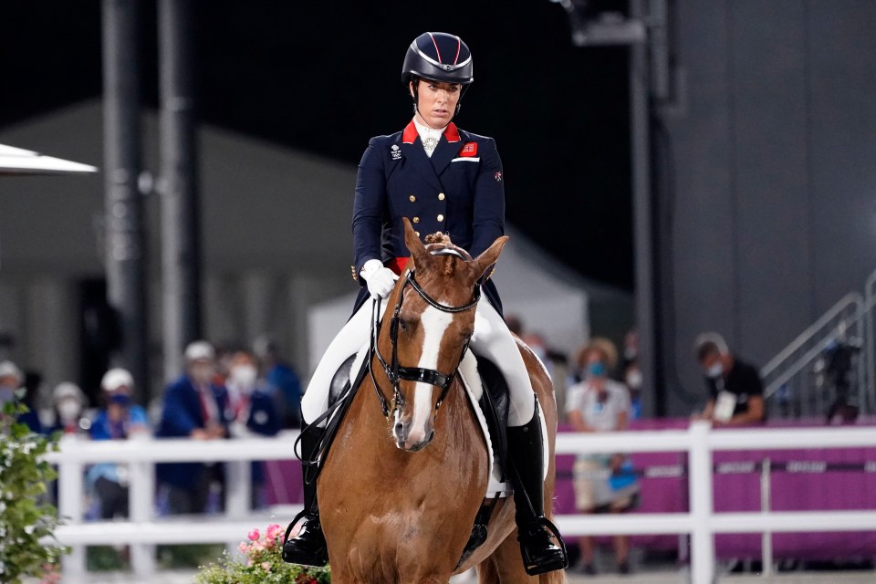 a woman riding a horse with a red and white stripe on her jacket