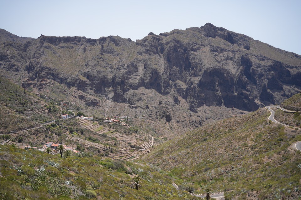 a valley with a mountain in the background and a road going through it