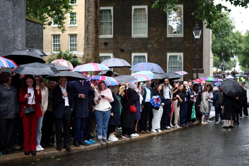 Labour Party supporters wait in the rain outside 10 Downing Street