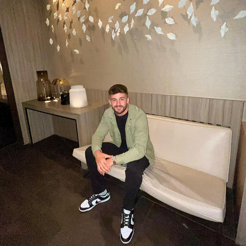 a man in a green jacket sits on a white couch