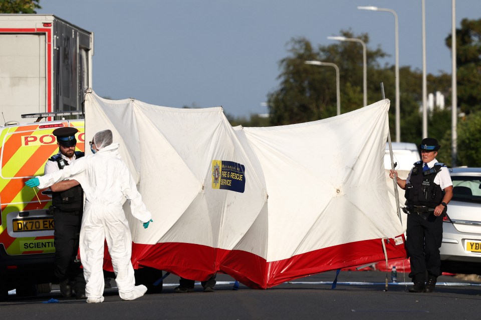 Police officers and forensic personnel put up a fence at the scene