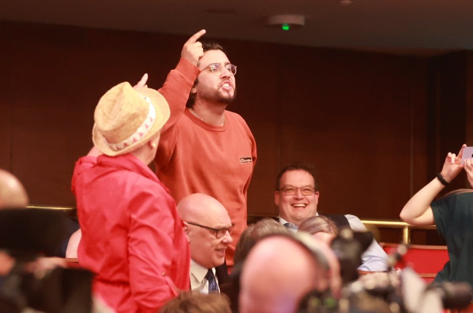 a group of people sitting in an auditorium with a man pointing at something