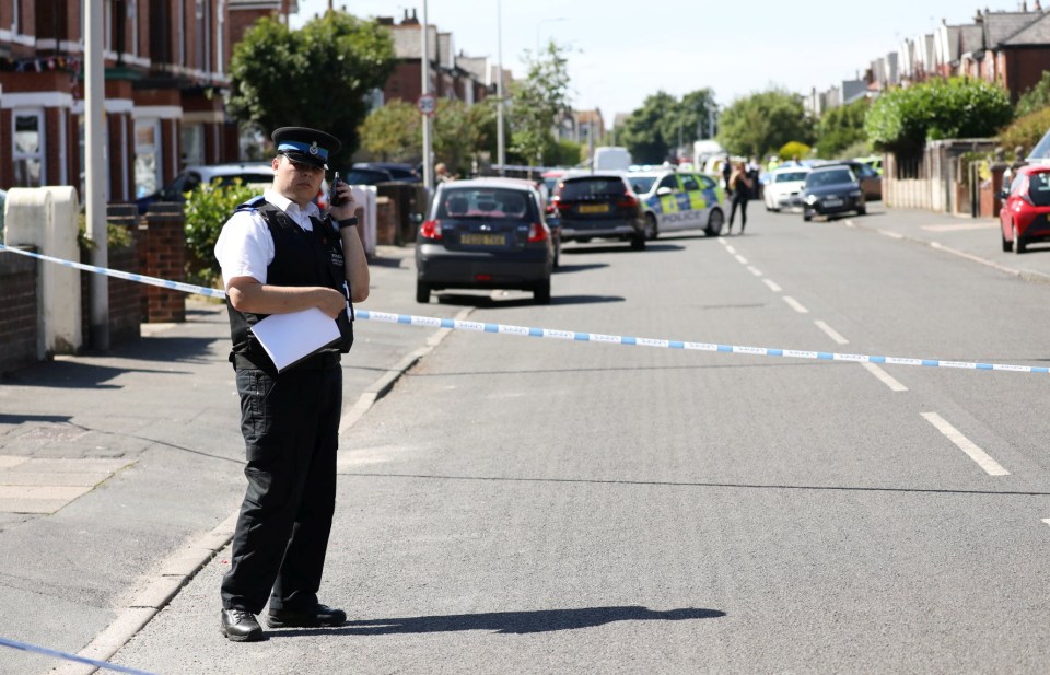 A police officer speaks on the phone while he guards the cordon