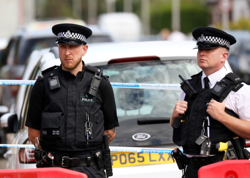 two police officers standing in front of a ford car