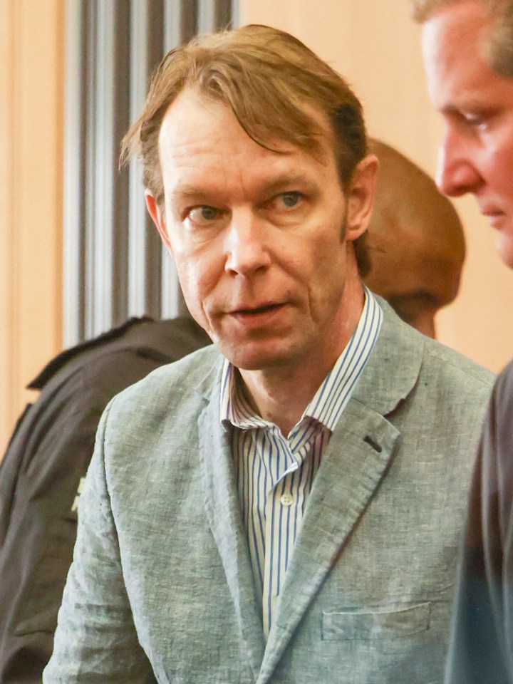 a man in a suit and striped shirt looks at the camera