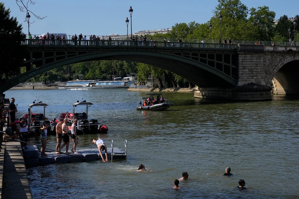 a group of people are swimming in a river under a bridge