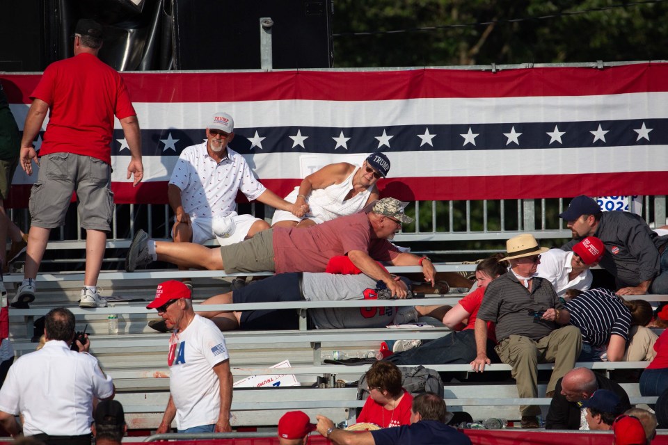 People in the crowd hide in the benches as shots are fired