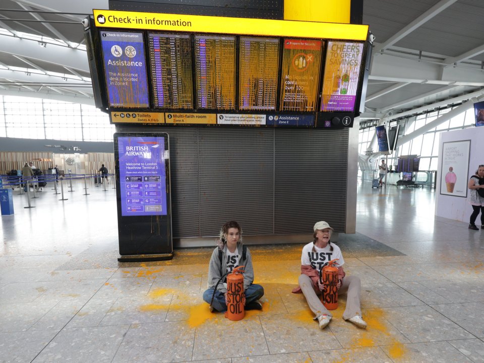 two people sit on the floor in front of a british airways sign