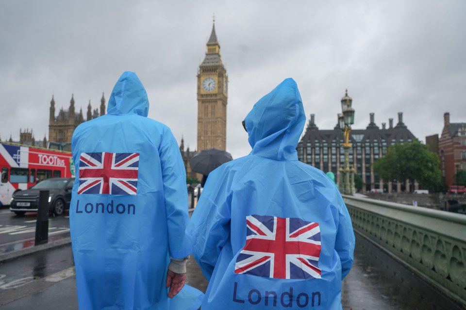 Tourists on Westminster Bridge wearing a rain poncho with a Union Jack