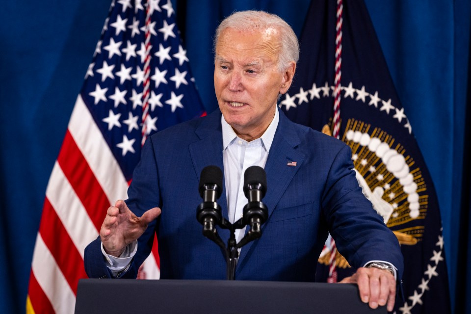 a man in a blue suit stands at a podium in front of two microphones