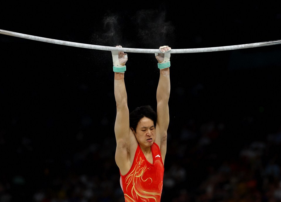 a man in a red tank top hangs from a bar