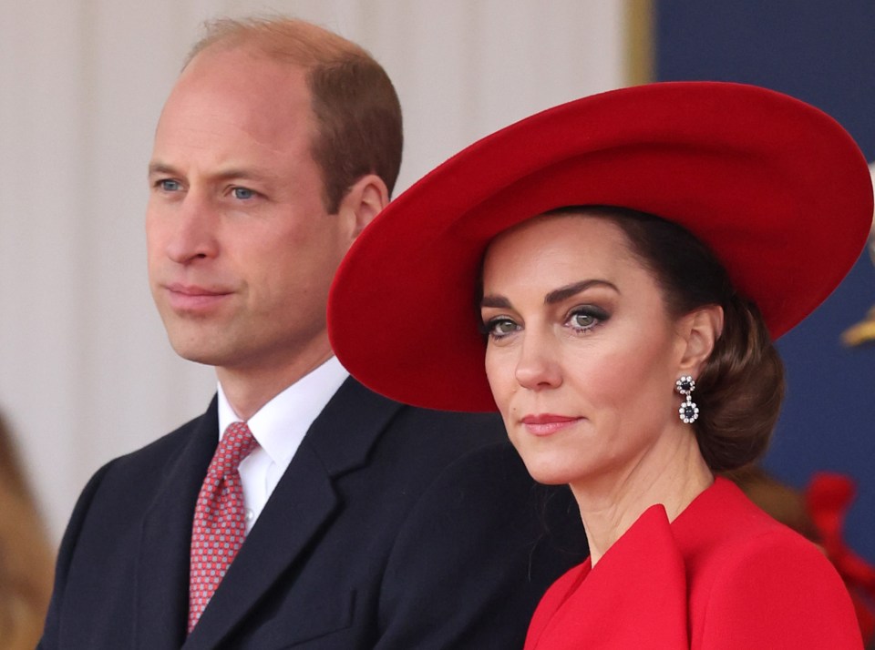 a man in a suit and tie stands next to a woman in a red hat