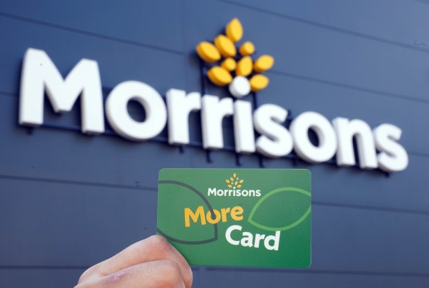 a person holding a morrisons more card in front of the store