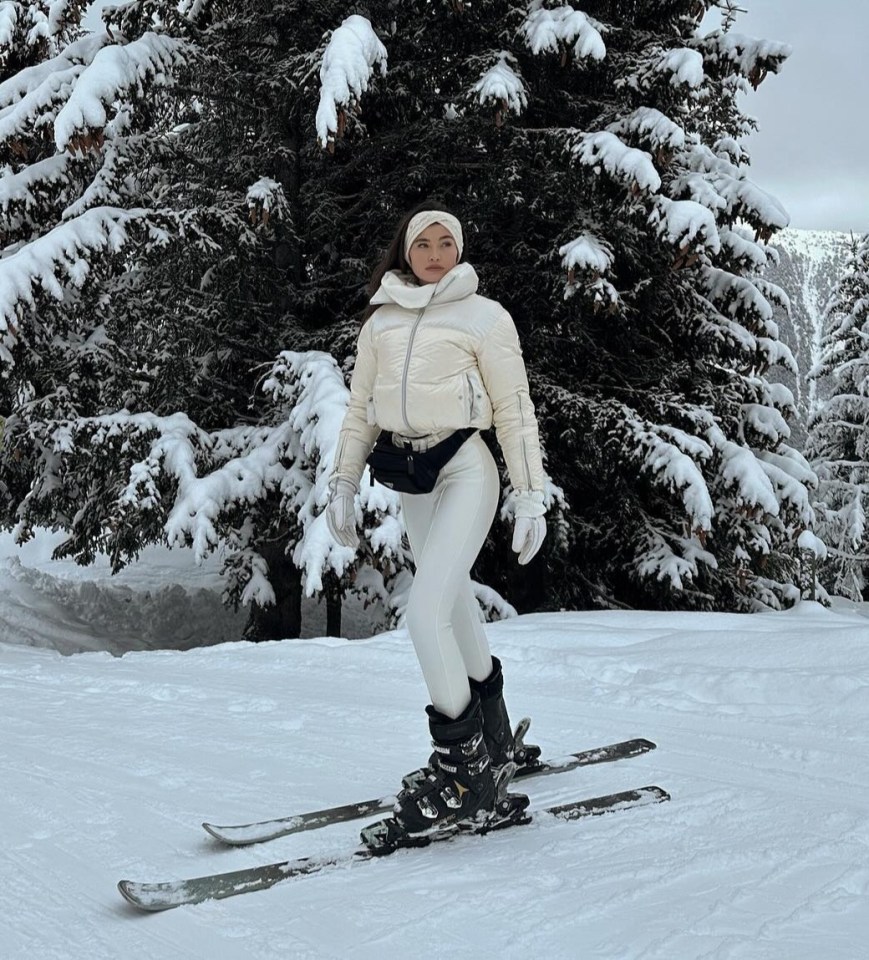 a woman stands on skis in front of a snow covered tree