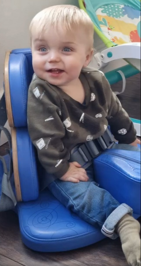 a baby is sitting on a blue chair and smiling