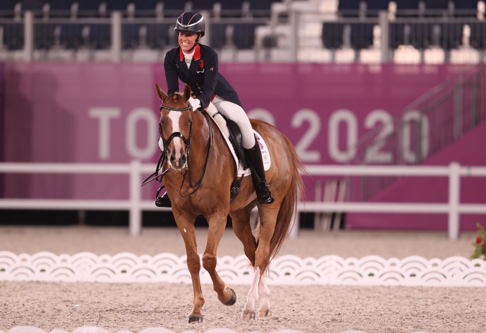 a woman riding a horse in front of a sign that says tokyo 2020