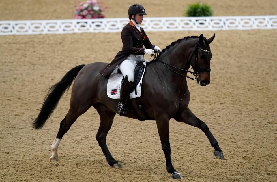 a woman riding a horse with a british flag on the saddle