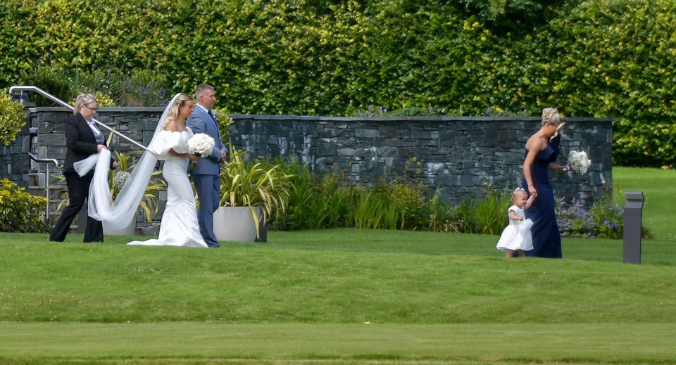 a bride and groom are walking down a grassy hill