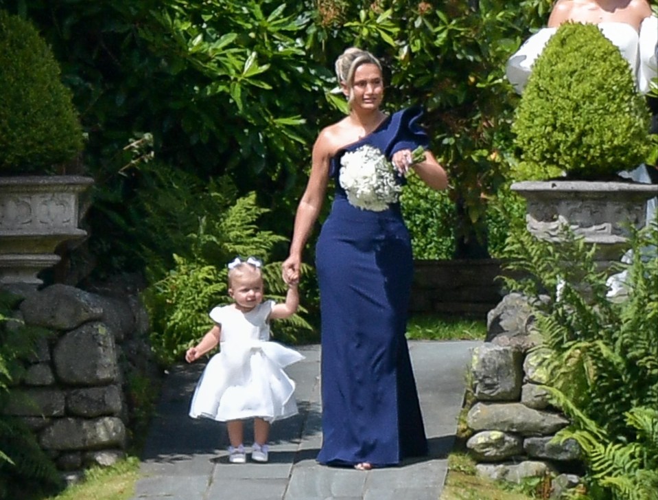 a woman in a blue dress holds the hand of a little girl