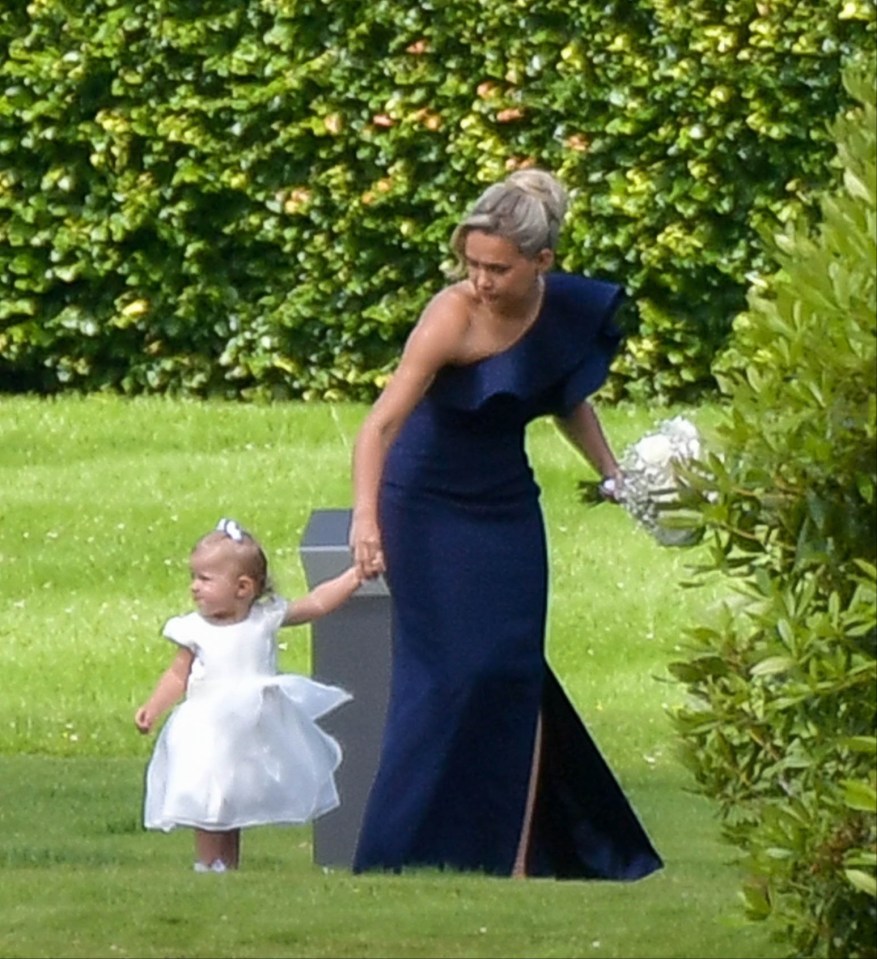 a woman in a blue dress holds the hand of a little girl in a white dress