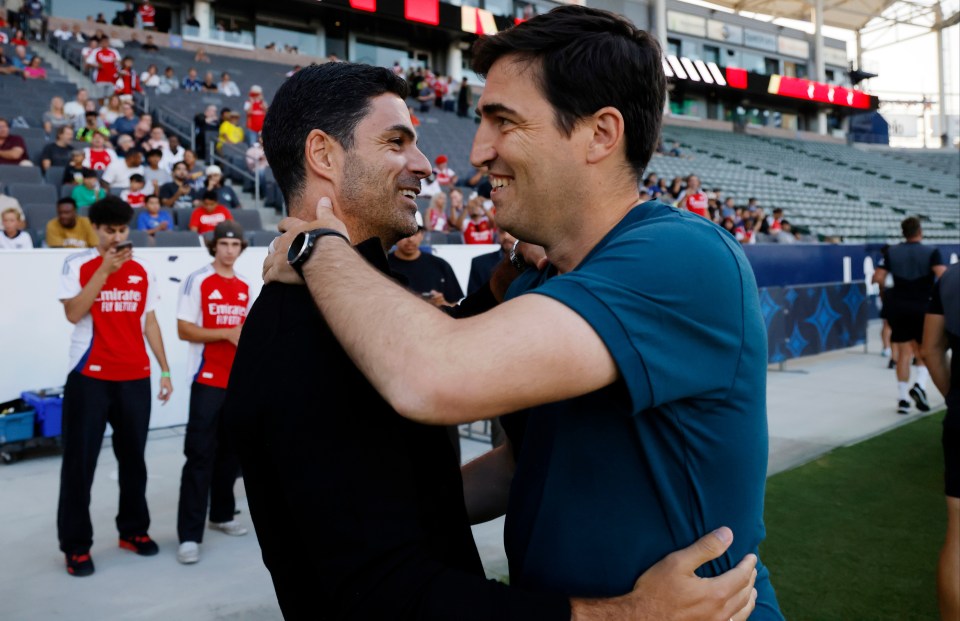 two men hugging with one wearing a shirt that says emirates fly better