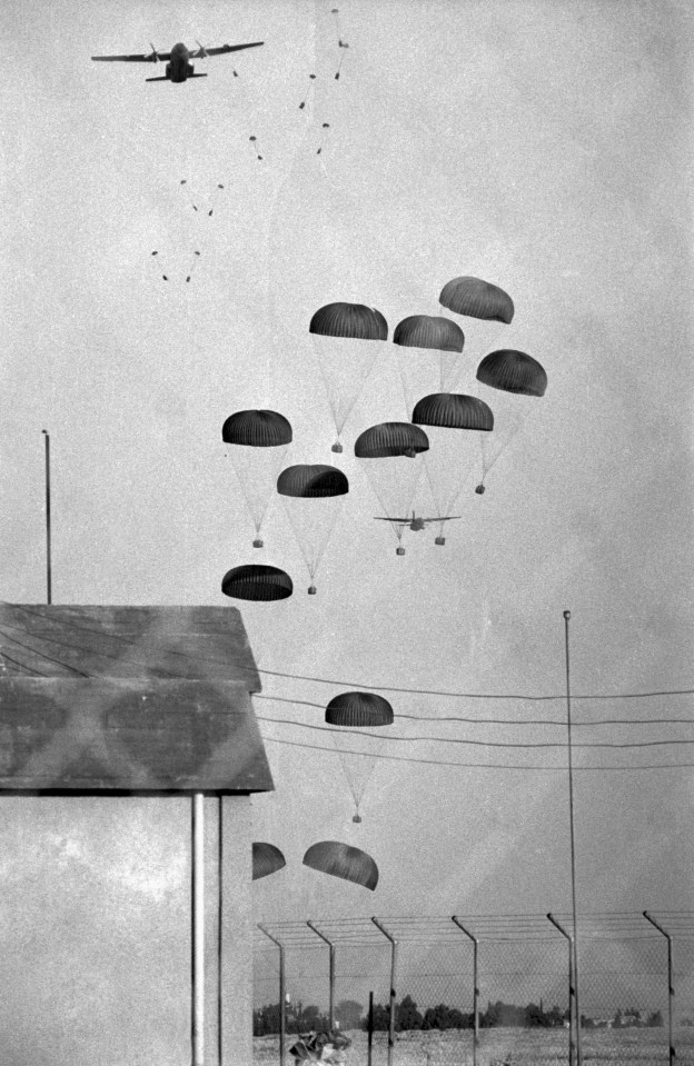 a black and white photo of parachutes being dropped from a plane