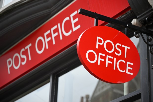 a red post office sign hangs outside of a building