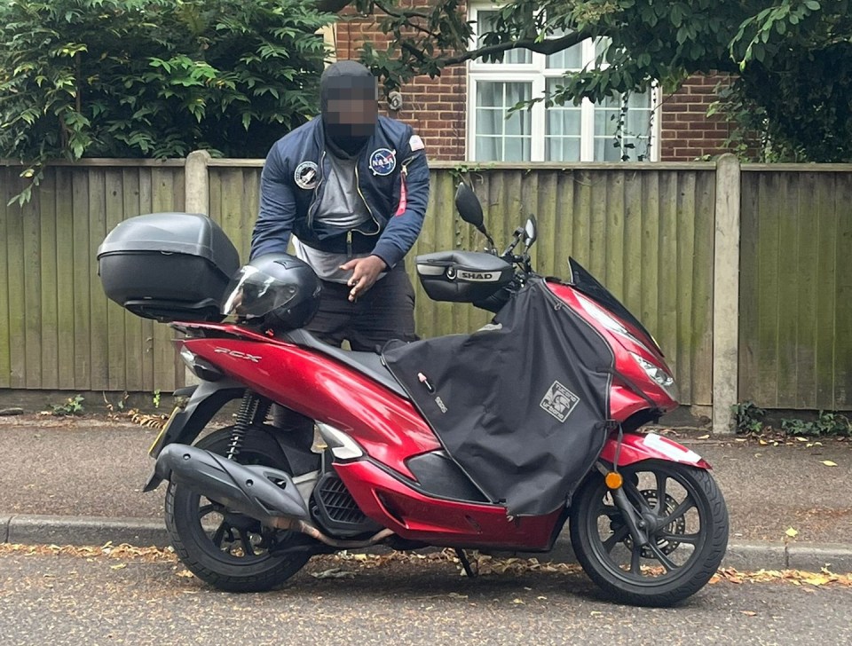 The alleged knifeman, wearing a NASA jacket and a ski mask, pictured behind a motorcycle at the scene