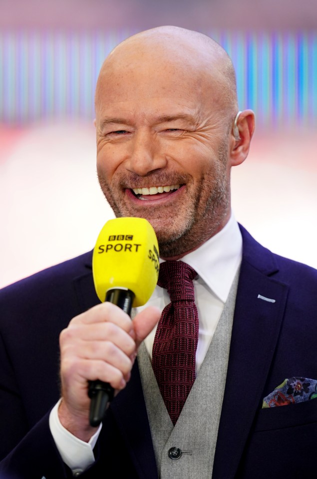 a man in a suit and tie is holding a yellow bbc sport microphone