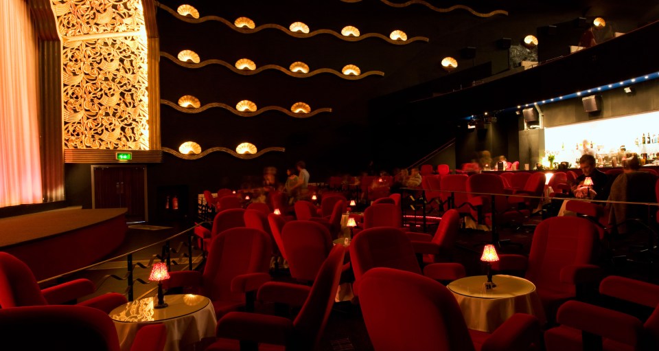 a theater with red seats and tables with candles on them