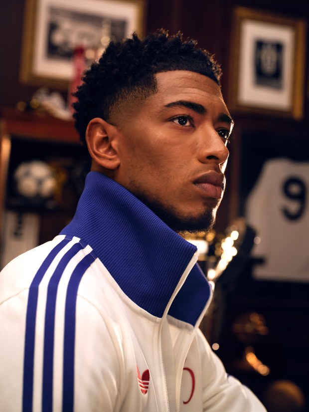 a man wearing a white adidas jacket with blue stripes