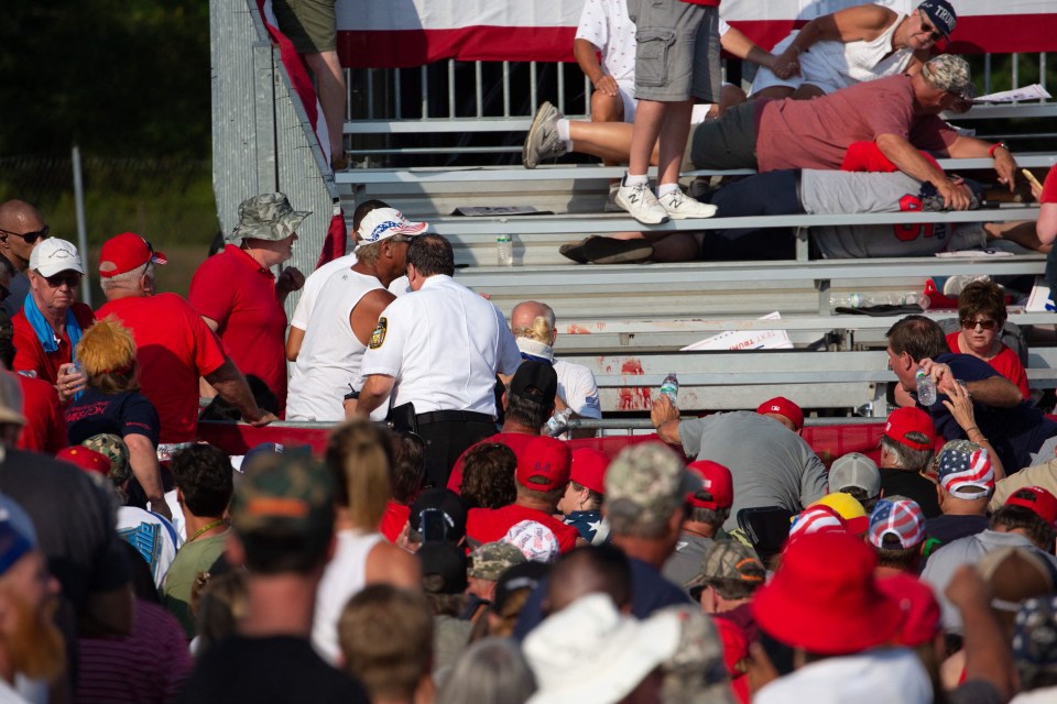 Trump supporters are seen laying in the stands after guns were fired at Republican candidate Donald Trump at a campaign event at Butler Farm Show Inc. in Butler, Pennsylvania, July 13, 2024. Republican candidate Donald Trump was evacuated from the stage at today's rally after what sounded like shots rang out at the event in Pennsylvania, according to AFP. The former US president was seen with blood on his right ear as he was surrounded by security agents, who hustled him off the stage as he pumped his first to the crowd. Trump was bundled into an SUV and driven away. (Photo by Rebecca DROKE / AFP) (Photo by REBECCA DROKE/AFP via Getty Images)