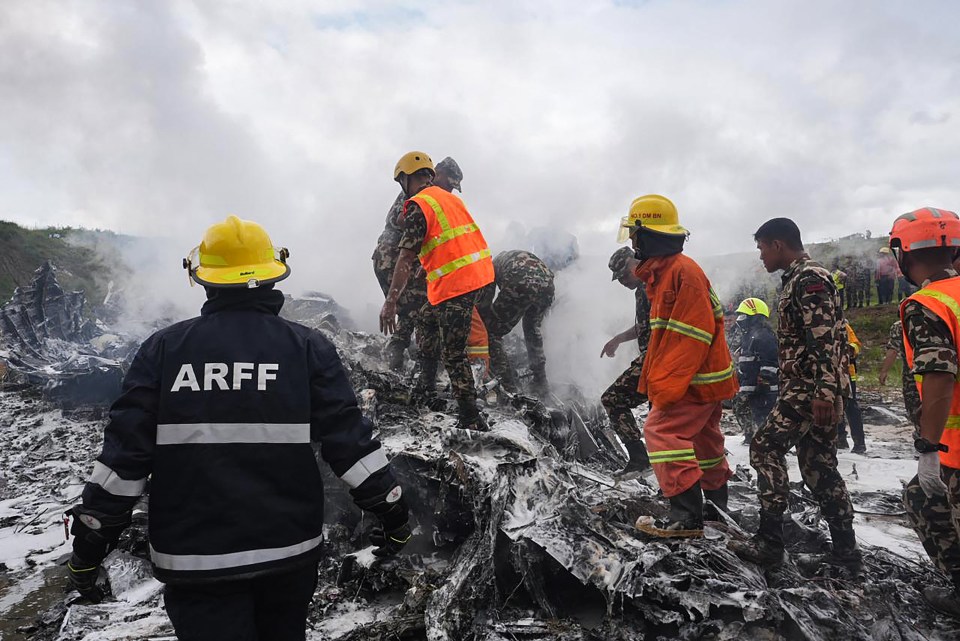 Rescuers and army personnel stand at the site after a Saurya Airlines' plane crashed during takeoff at Tribhuvan International Airport in Kathmandu on July 24, 2024. A passenger plane carrying 19 people crashed during takeoff in Kathmandu on July 24 with the pilot surviving but "many" others aboard dead, police in the Nepali capital told AFP. (Photo by Prabin RANABHAT / AFP) (Photo by PRABIN RANABHAT/AFP via Getty Images)