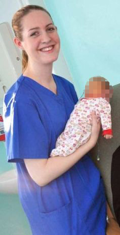 a woman in a blue scrub is holding a baby in her arms .