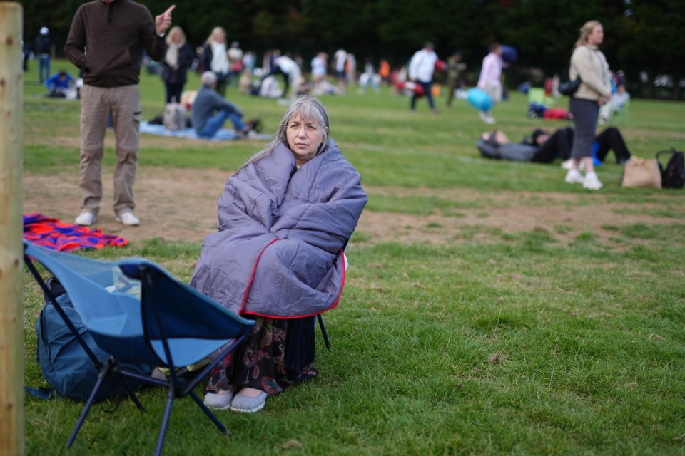 A tennis fan wraps herself in a blanket in the queues