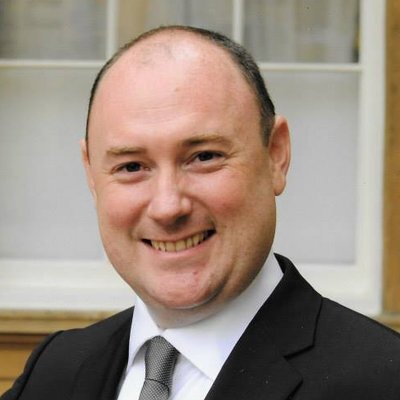 a man in a suit and tie is smiling for the camera .