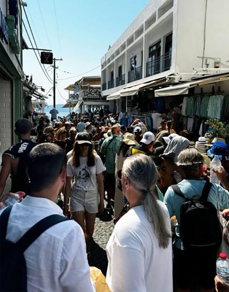 a crowd of people walking down a street with a sign that says ' x ' on it