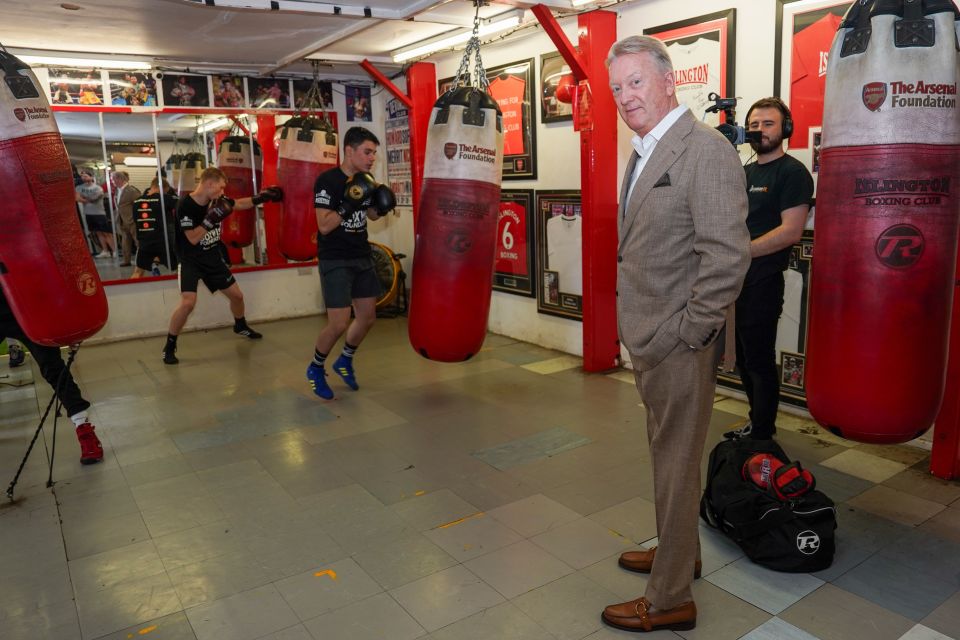 a man in a suit stands in a boxing gym